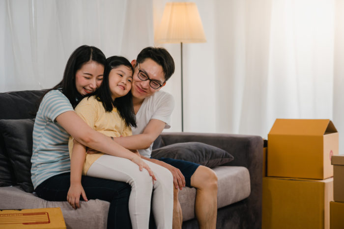 happy asian young family homeowners bought new house japanese mom dad daughter embracing looking forward future new home after moving relocation sitting sofa with boxes together 700x467 - Ketahui 7 Macam Hak Anak yang Wajib Dipenuhi Orang Tua