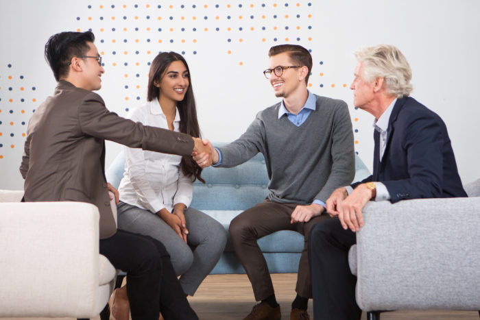 smiling business partners shaking hands lounge 700x467 - 5 Langkah Mudah Fresh Graduate Mendapatkan Pekerjaan