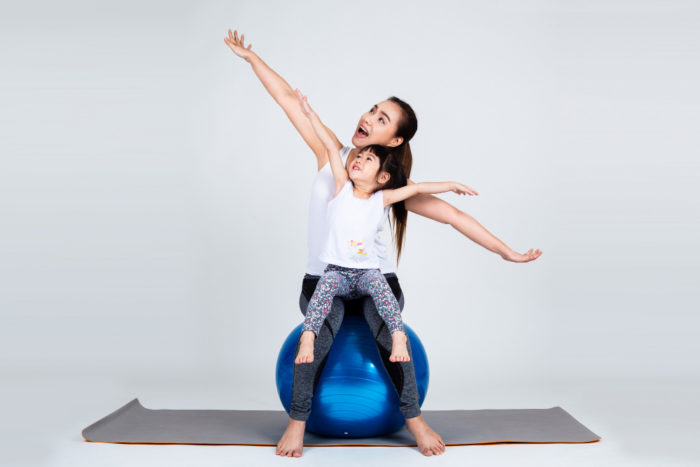 young mother with little daughter exercise fitness ball 700x467 - Ketahui Efek Buruk dan Cara Atasi Kecanduan Gadget pada Anak