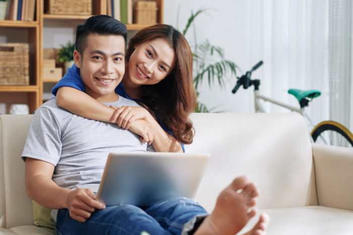 asian man relaxing couch with laptop home happy woman hugging him 700x467 - Bekerja di Rumah Jadi Menyenangkan dengan 7 Tips Berikut Ini