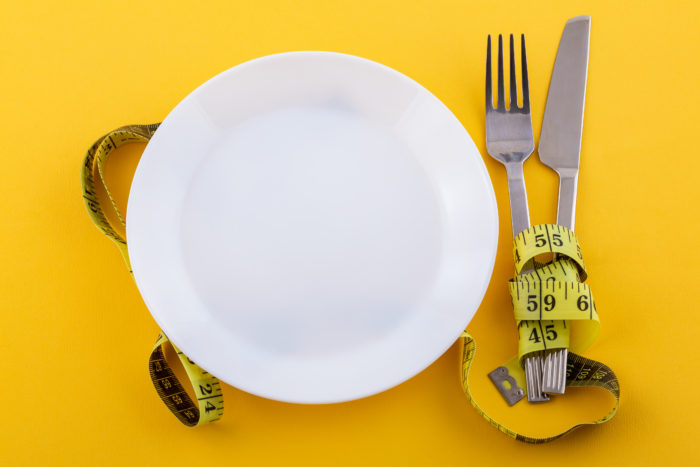 cutlery white plate with measuring tape yellow concept weight loss diet 700x467 - Tubuh Mudah Merasa Lelah? Ketahui Penyebab dan Cara Mengatasinya